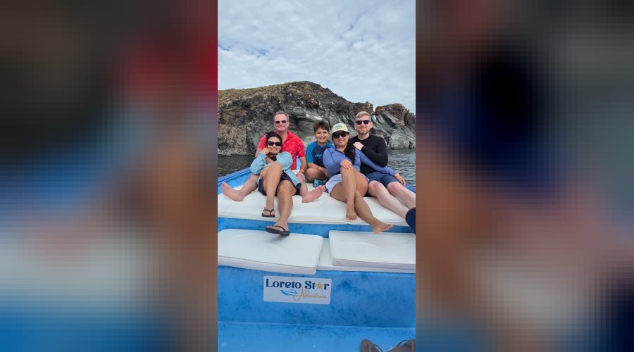 Familia sentada en la proa de la panga Loreto Star frente a los acantilados de una isla en Loreto